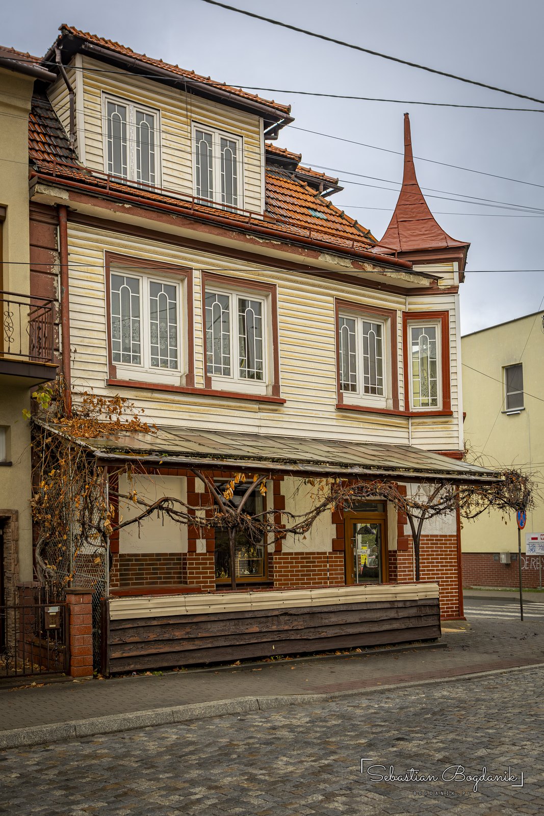 Kamienica z wieżyczką i drewnianą werandą.