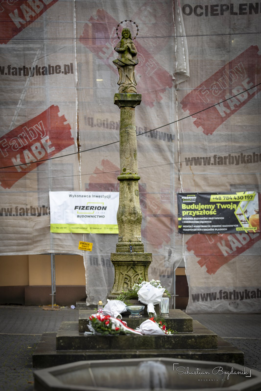 Kolumna z figurą przed odnawianą kamienicą.