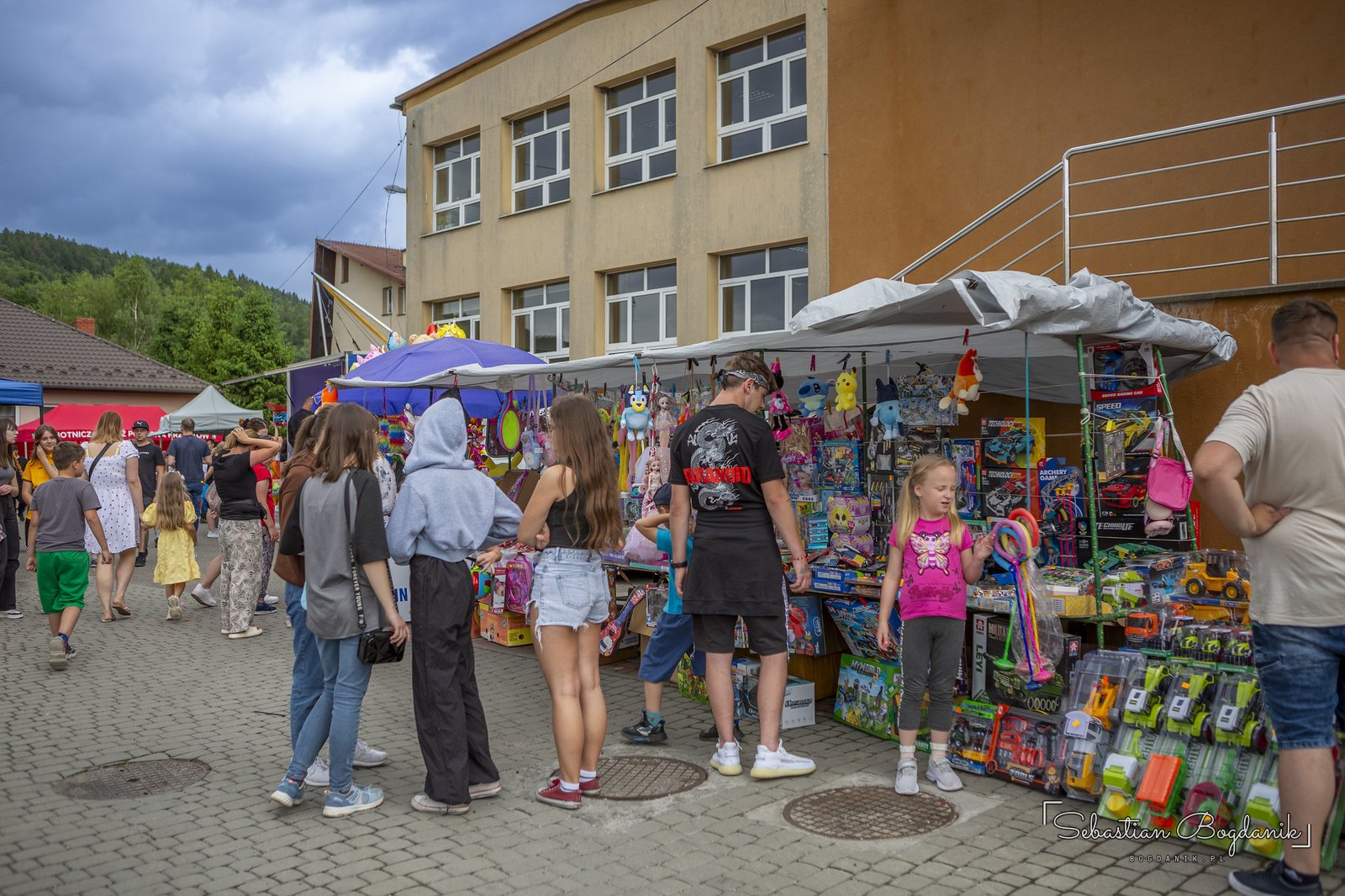 The fair by the stage: toys, crafts and crowds despite the clouds.