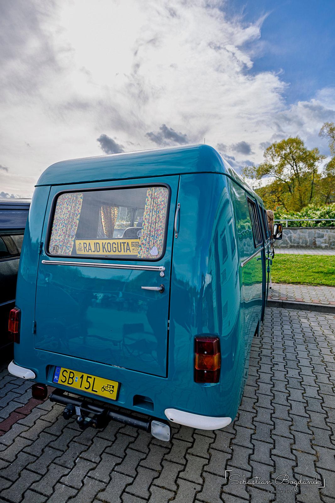 A Nysa van turned camper: curtains in the back, a camping stove with a kettle, a rug and a jug of water (1/2)