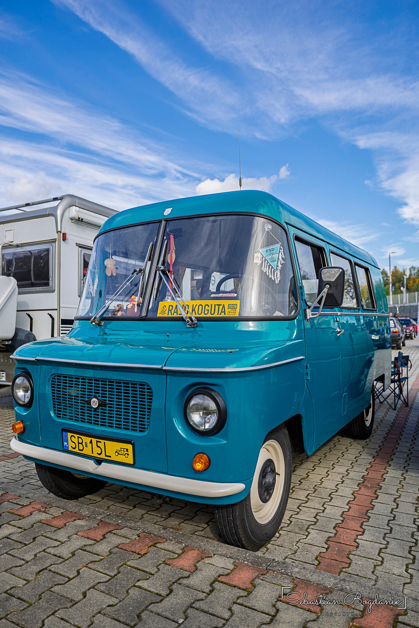 A turquoise Nysa with white wheels and a chrome bumper standing on paving stones.