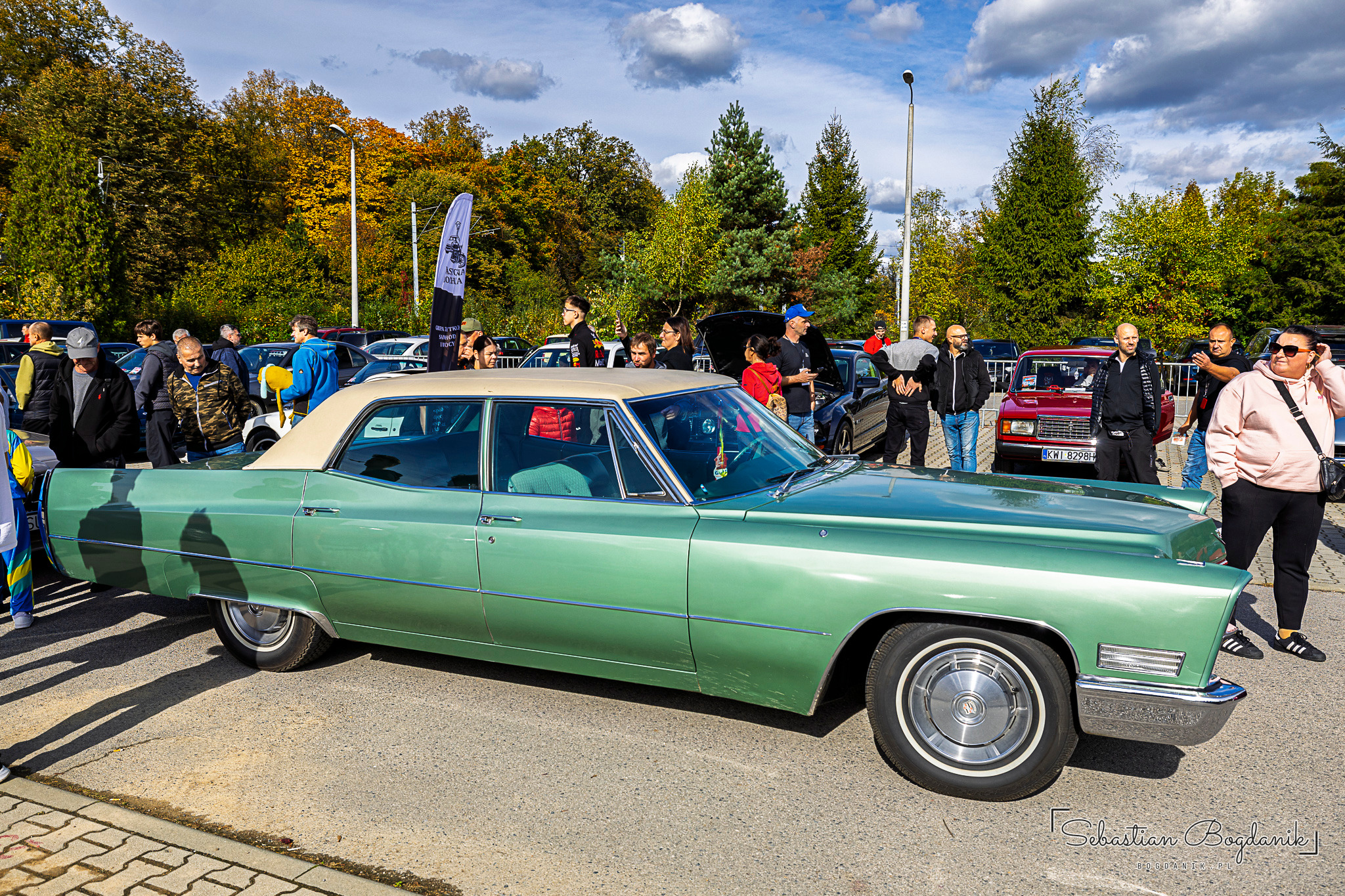 A long green American sedan with a light-coloured roof, surrounded by a crowd of visitors.